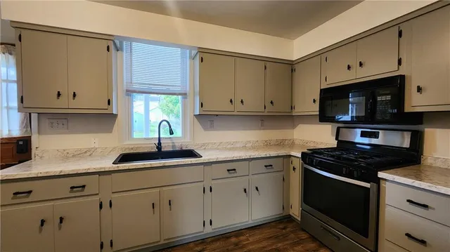a kitchen with granite countertop white cabinets white stainless steel appliances and a sink