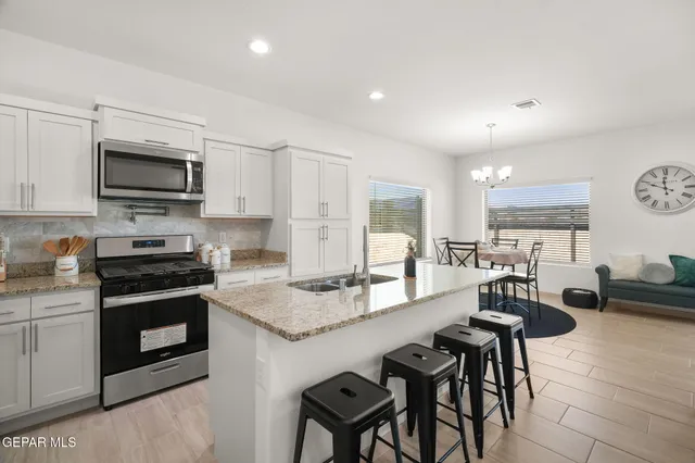 a kitchen with granite countertop a stove a sink a dining table and chairs