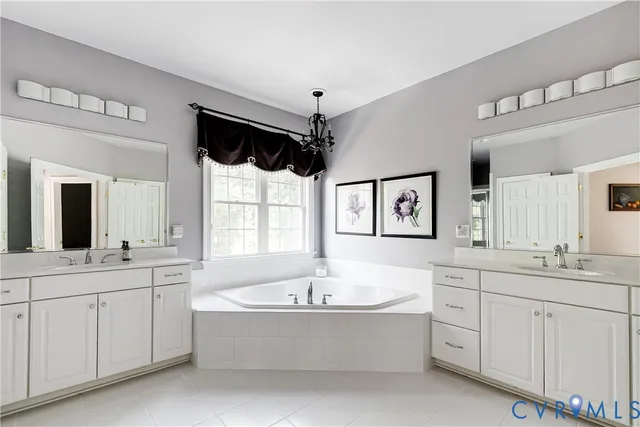 a bathroom with a bathtub a double vanity sink a mirror a window and vanity