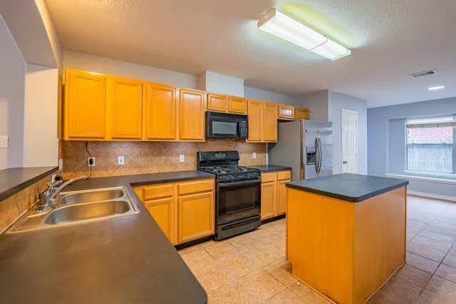 a kitchen with granite countertop a sink and a stove top oven