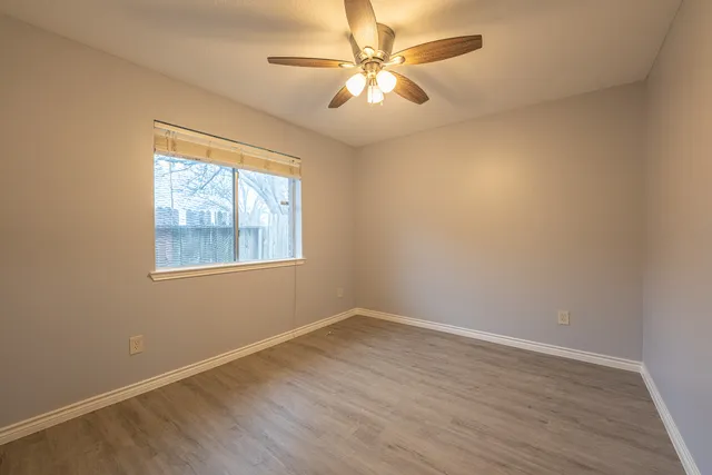 an empty room with a window and a fan