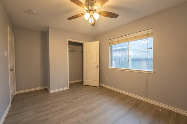 a view of an empty room with window and wooden floor