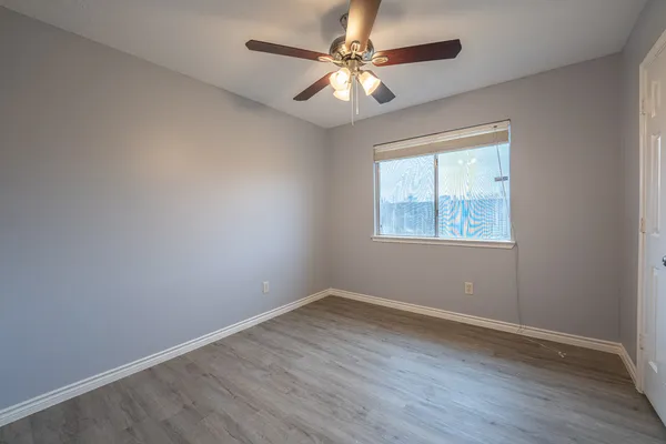 an empty room with a window and a fan