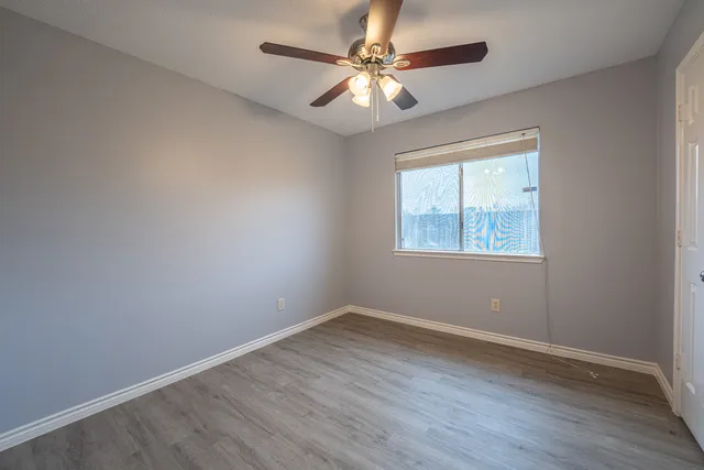 an empty room with a window and a fan