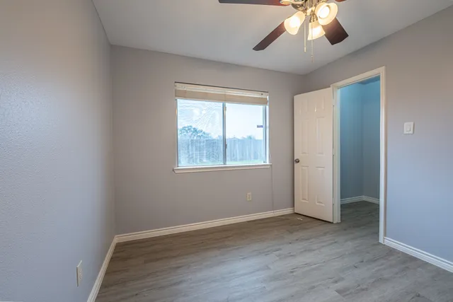 an empty room with wooden floor chandelier and windows