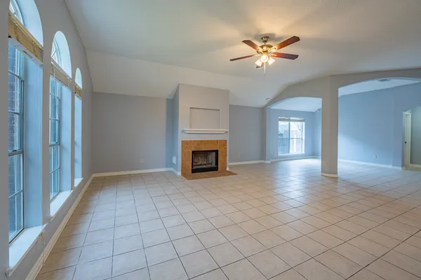 a view of an empty room with a fireplace and a chandelier fan