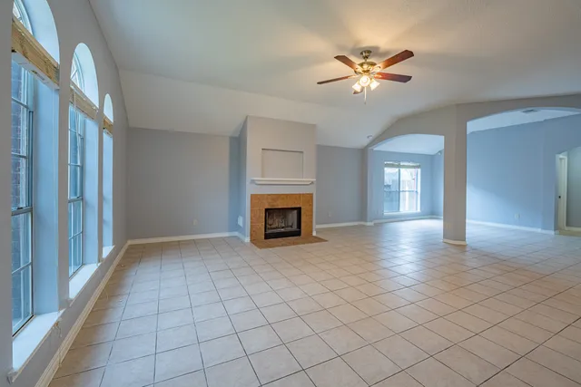 a view of an empty room with a fireplace and a chandelier fan