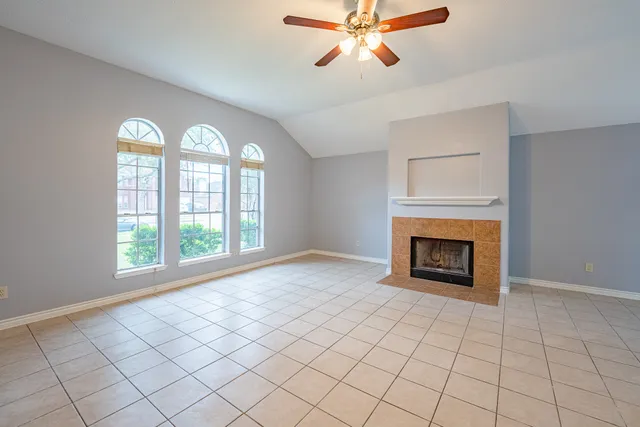 an empty room with windows and fireplace