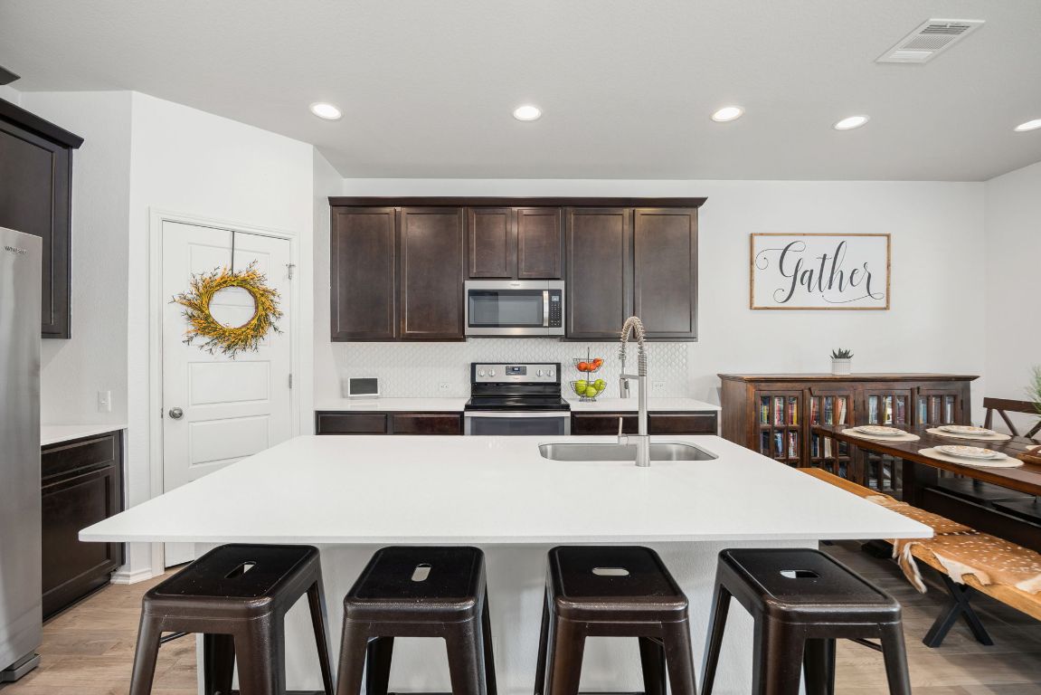 1340 Terrace View Drive Georgetown, TX 78628 - Photo 4 of 25 a kitchen with stainless steel appliances a dining table chairs and refrigerator