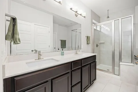 a bathroom with a double vanity sink mirror and shower