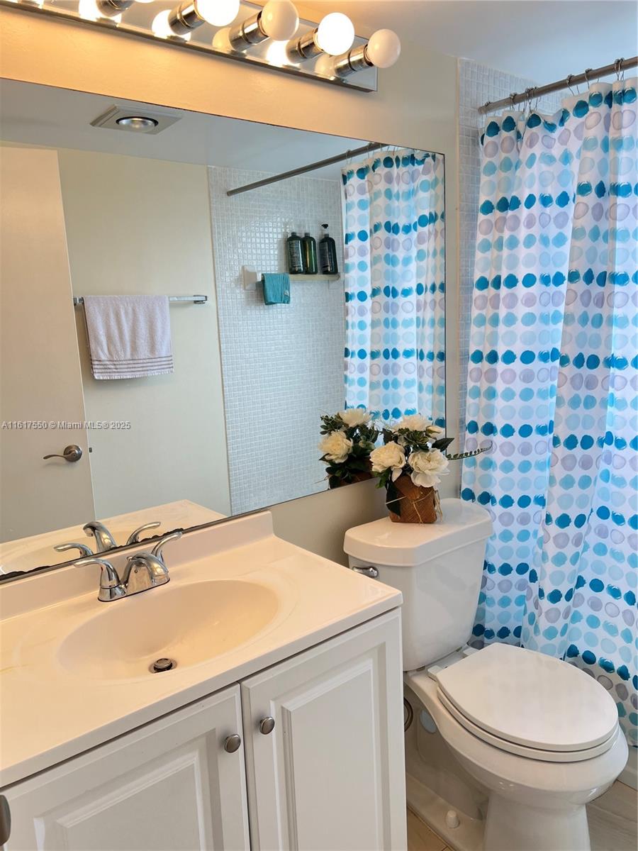 155 Suffolk F, Unit D Boca Raton, FL 33434 - Photo 23 of 41 a bathroom with a sink a toilet and shower curtain
