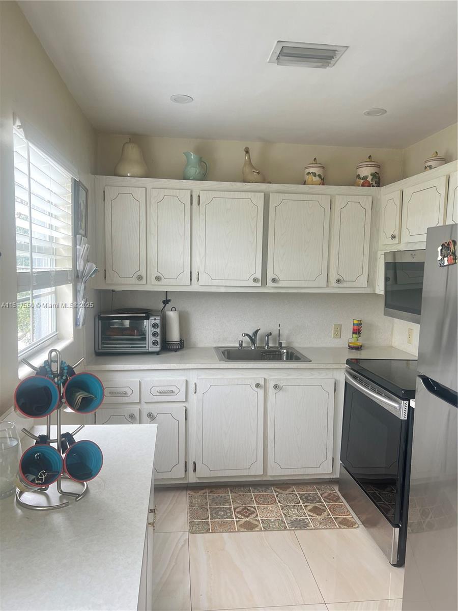 155 Suffolk F, Unit D Boca Raton, FL 33434 - Photo 35 of 41 a kitchen with cabinets a sink and appliances