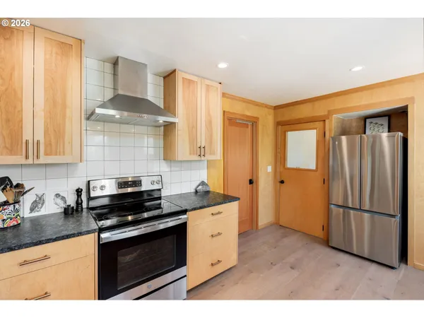 a kitchen with stainless steel appliances granite countertop a stove a refrigerator and a sink with wooden cabinets