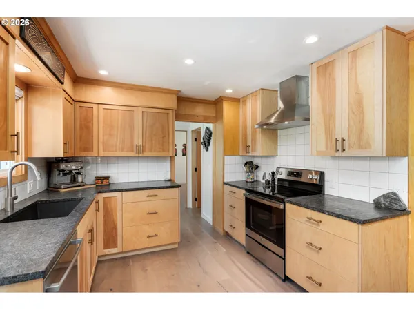 a kitchen with stainless steel appliances granite countertop a sink a stove and a refrigerator