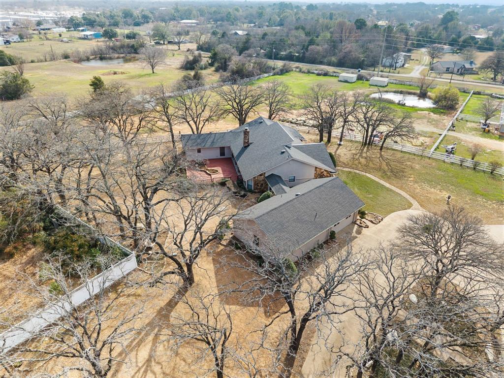 7260 Hudson Cemetery Road Mansfield, TX 76063 - Photo 7 of 40 Expansive property featuring a residence with a gray shingle roof, a detached structure with a gray shingle roof, mature deciduous trees, a paved driveway, and a pond