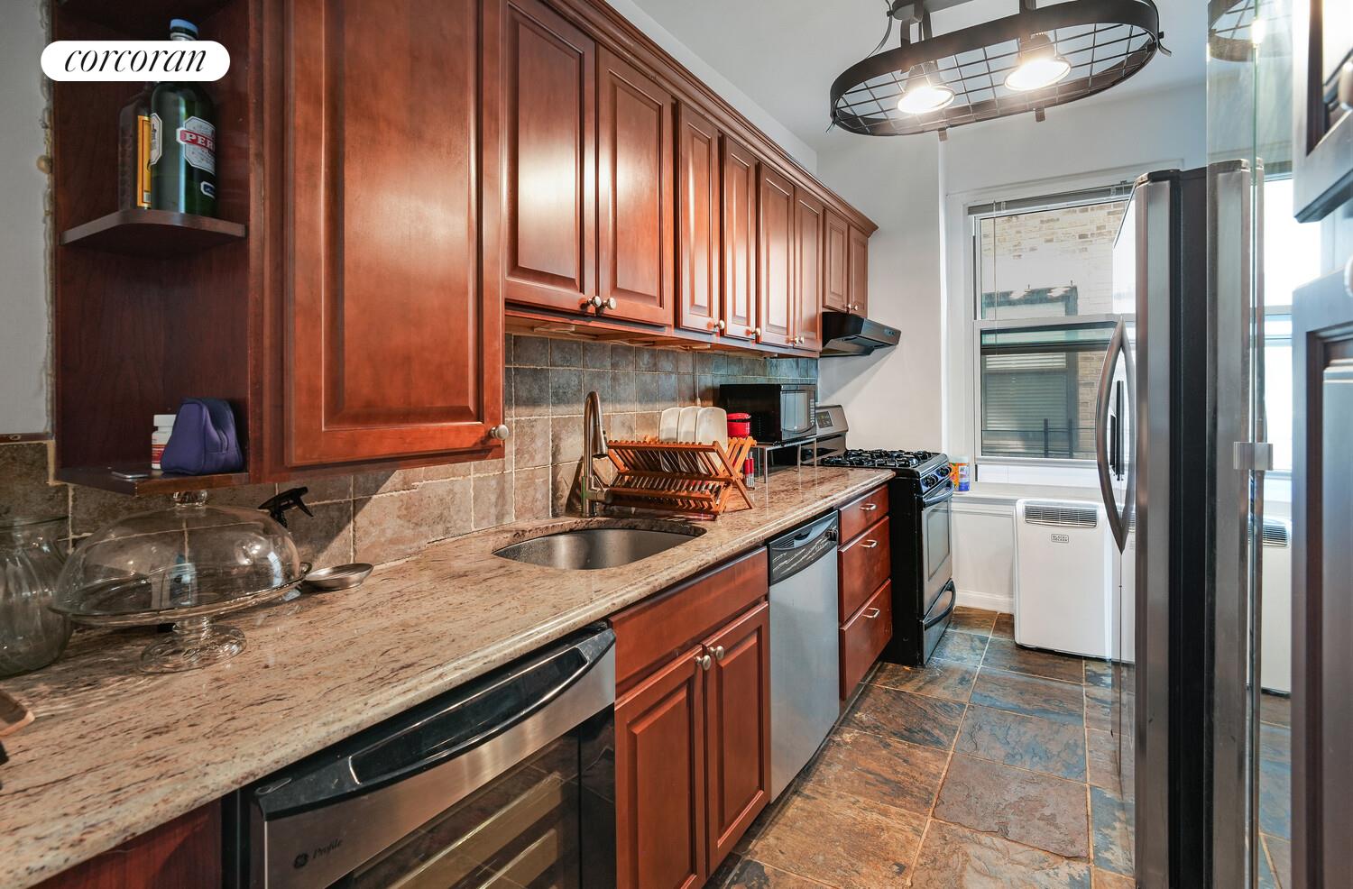 875 West 181st Street, Unit 4L Manhattan, NY 10033 - Photo 11 of 18 a kitchen with granite countertop stainless steel appliances and wooden cabinets