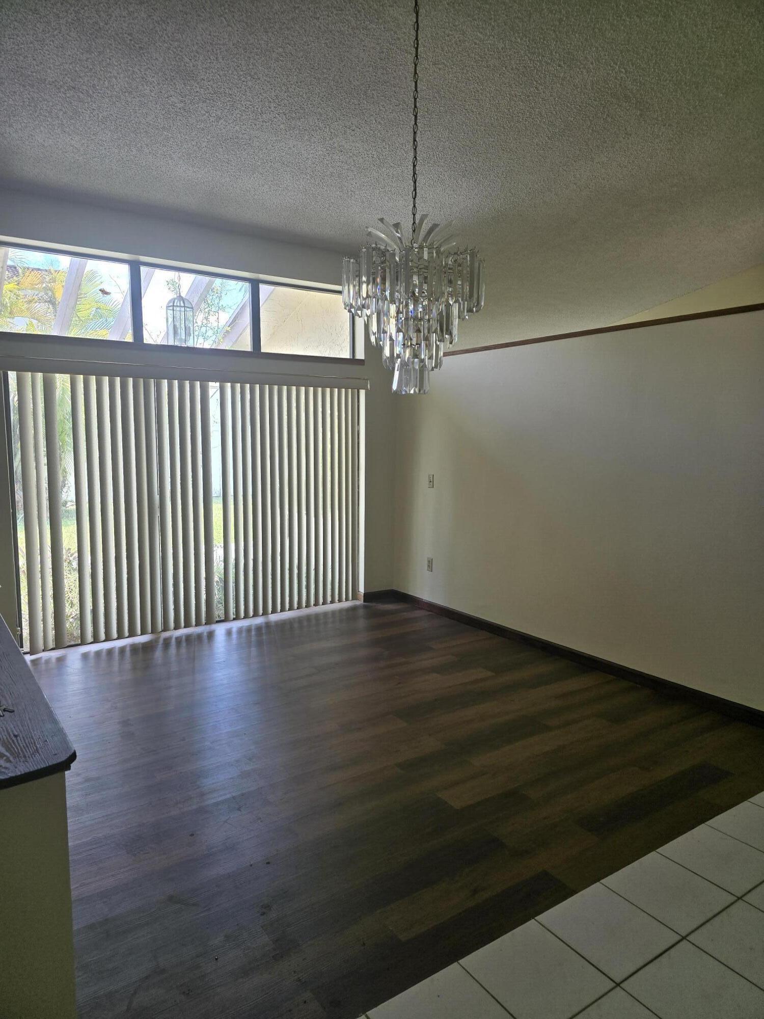 12730 Southwest 112th Street Miami, FL 33186 - Photo 7 of 11 a view of a livingroom with wooden floor and chandelier