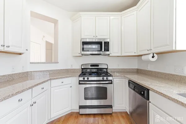a kitchen with granite countertop white cabinets and white appliances