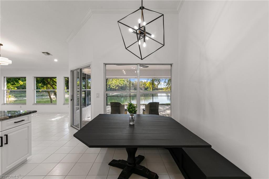 7867 Gardner Drive Naples, FL 34109 - Photo 12 of 36 Dining room featuring suspended lighting, crown molding, light tile patterned floors, a water view, and a high ceiling