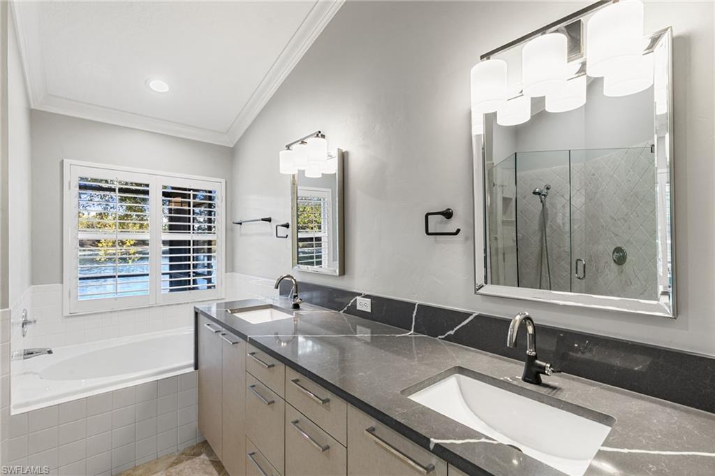 7867 Gardner Drive Naples, FL 34109 - Photo 17 of 36 Full bathroom featuring a stall shower, double vanity, a garden tub, and crown molding