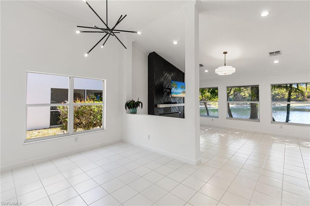 7867 Gardner Drive Naples, FL 34109 - Photo 3 of 36 Unfurnished living room with a chandelier, light tile patterned floors, ornamental molding, and lofted ceiling