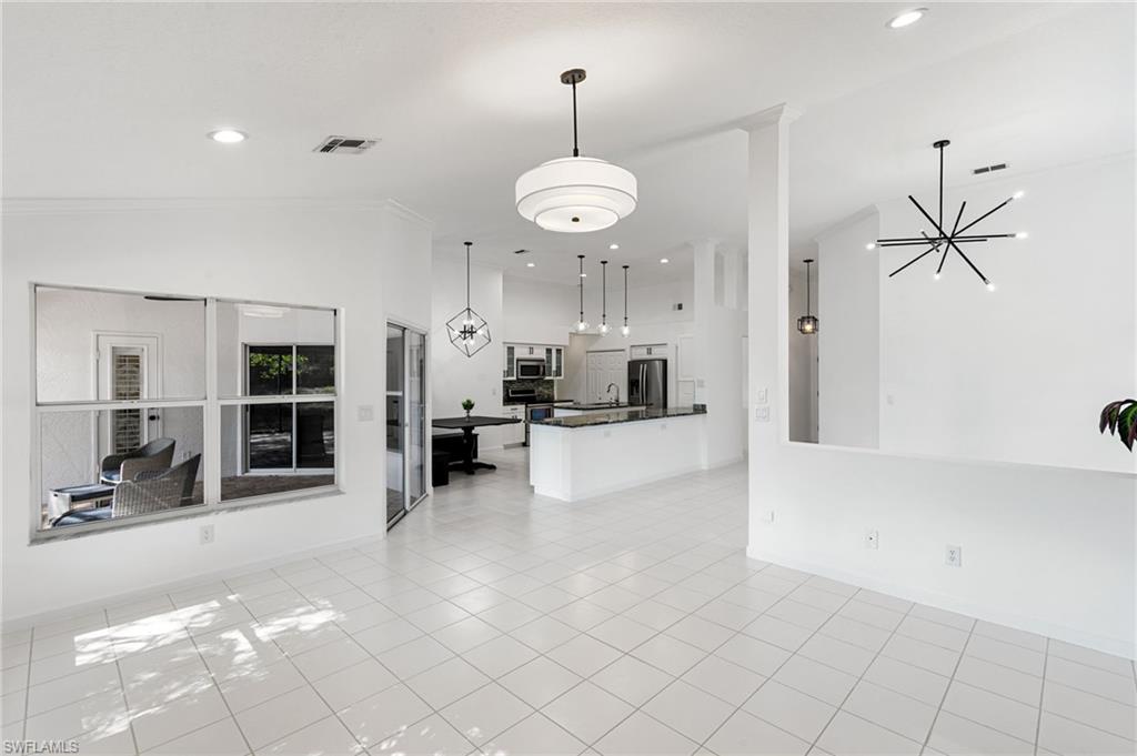 7867 Gardner Drive Naples, FL 34109 - Photo 7 of 36 Unfurnished living room with suspended lighting and light tile patterned floors