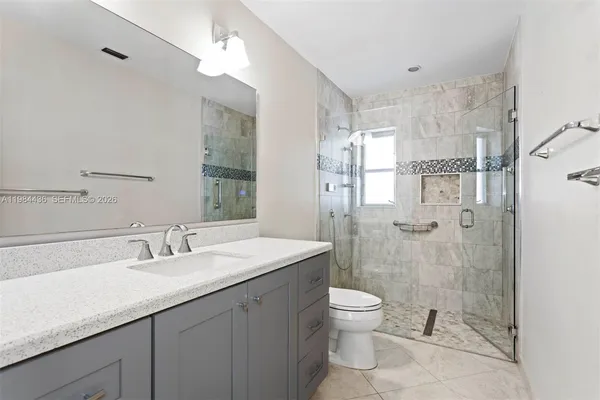 a bathroom with a granite countertop sink a toilet a mirror and shower