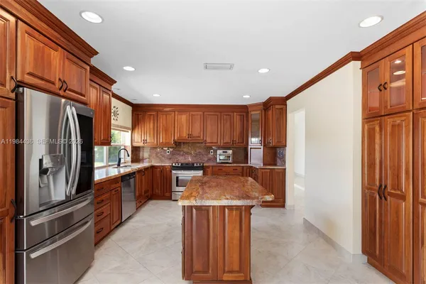 a kitchen with stainless steel appliances granite countertop a refrigerator a sink a stove and island