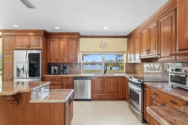 a kitchen with stainless steel appliances granite countertop a stove top oven a sink dishwasher and a microwave oven with white cabinets