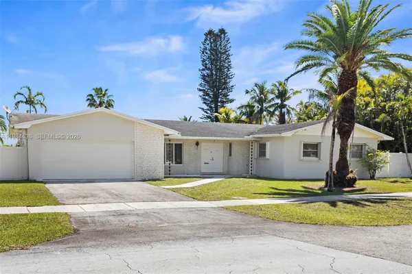 a view of a white house with a yard and potted plants
