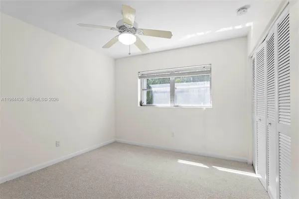 an empty room with a chandelier fan and windows
