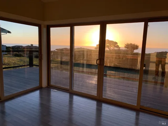 a view of an empty room with wooden floor and a floor to ceiling window