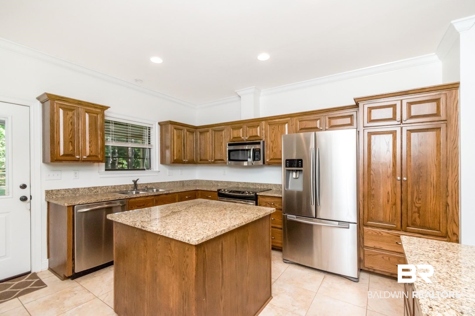 1360 Dykes Road North Mobile, AL 36608 - Photo 14 of 40 Kitchen with stainless steel appliances, brown cabinetry, light stone countertops, ornamental molding, and a center island
