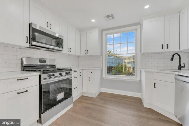 a kitchen with stainless steel appliances granite countertop a stove a sink and a microwave