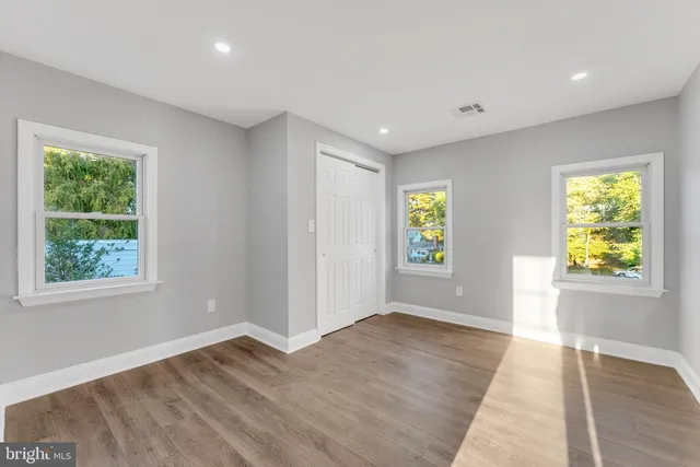 a view of an empty room with window and wooden floor