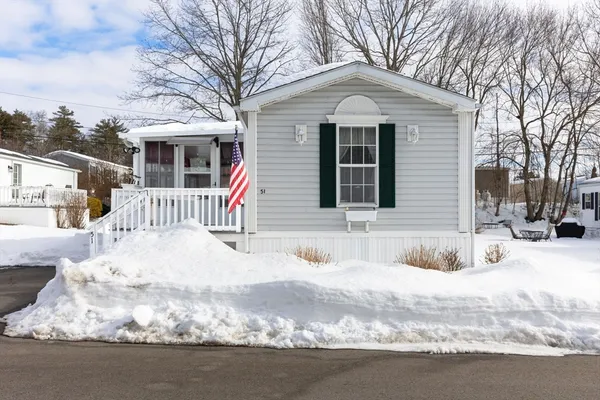 a front view of a house with a yard covered in snow