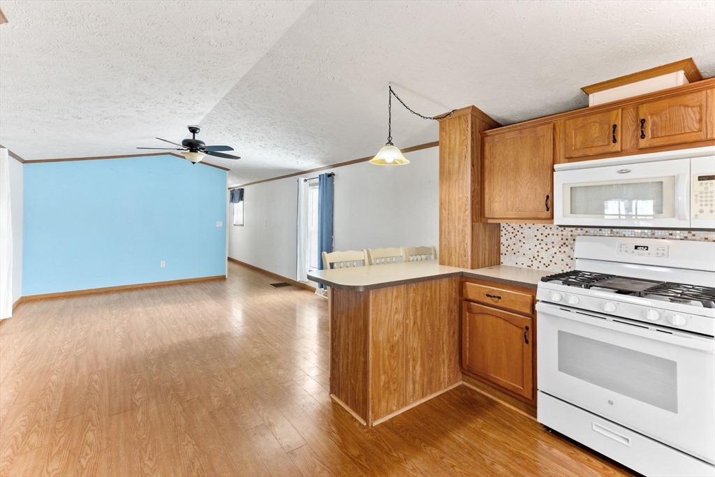 51 Tucker Terrace Raynham, MA 02767 - Photo 16 of 35 a kitchen with granite countertop a stove and a wooden floors