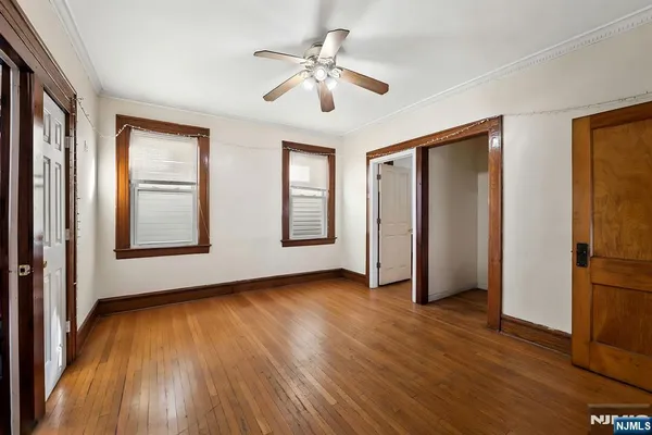 a view of an empty room with window and wooden floor