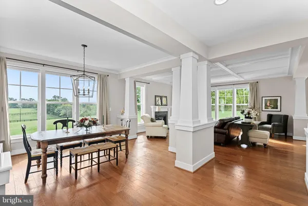 a dining room with wooden floor a chandelier a glass table and chairs