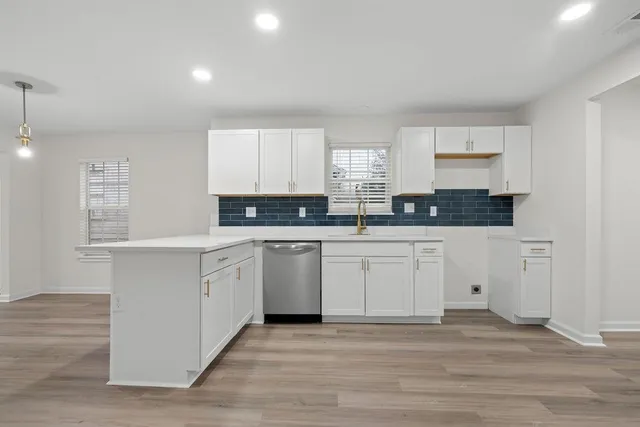 a kitchen with stainless steel appliances granite countertop a stove a sink and white cabinets