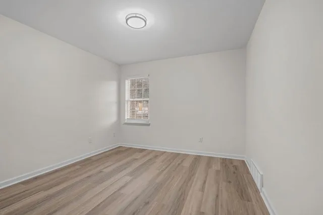 an empty room with a hardwood and a window