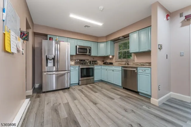 a kitchen with stainless steel appliances granite countertop a refrigerator a sink dishwasher a stove and a microwave oven with wooden floor