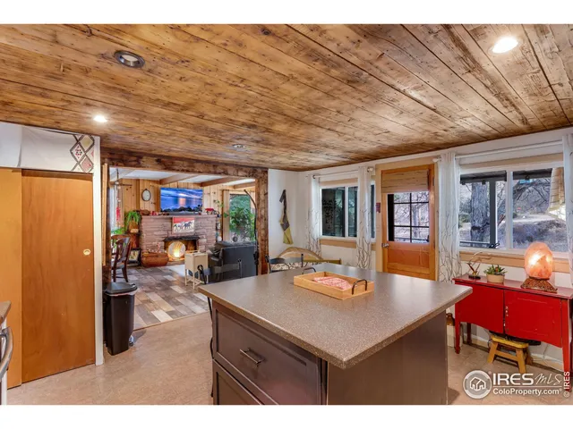 a kitchen with stainless steel appliances kitchen island granite countertop a stove top oven a sink dishwasher and white cabinets with wooden floor