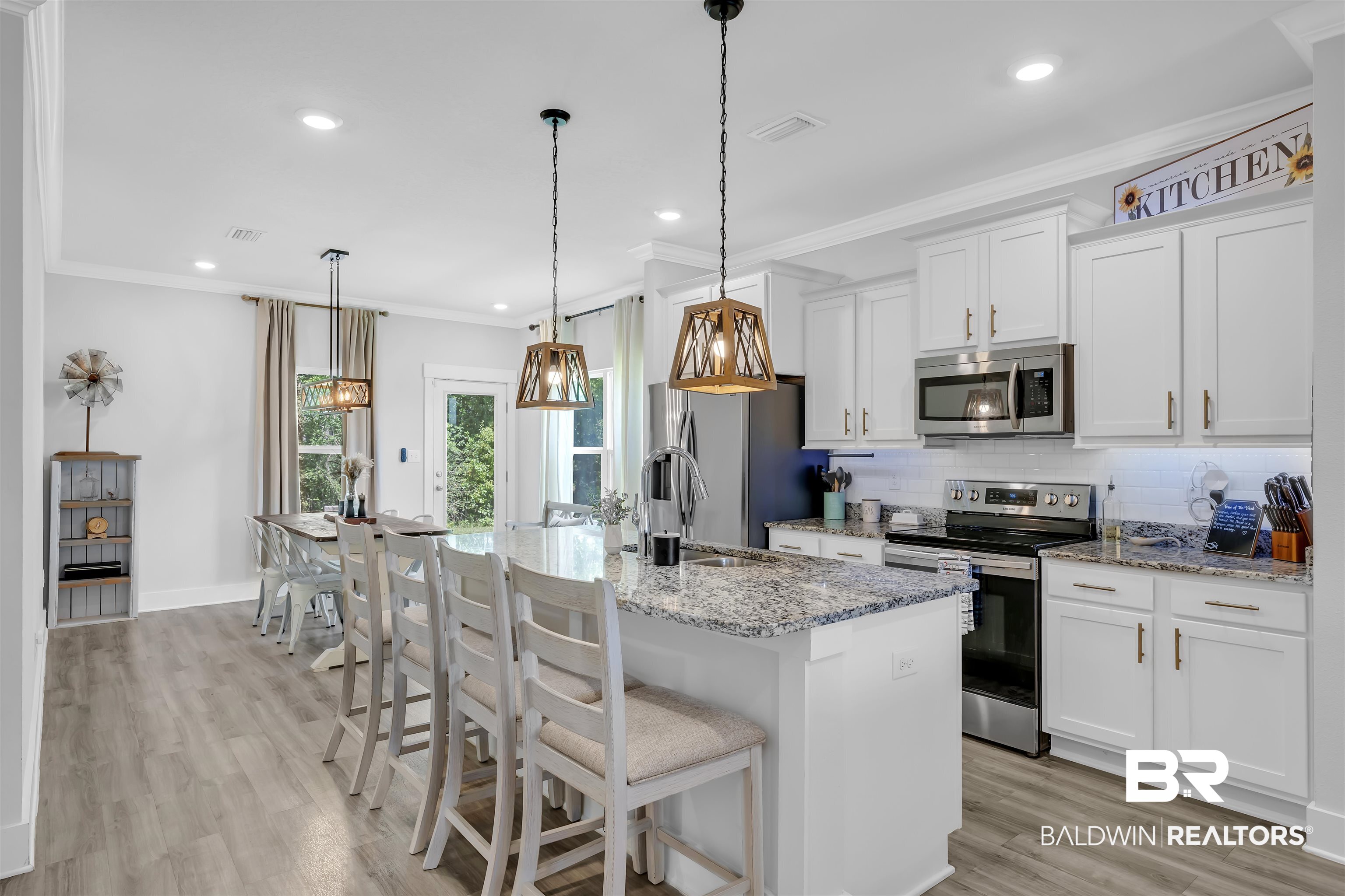 16504 Prado Loop Loxley, AL 36551 - Photo 10 of 45 Kitchen featuring a kitchen bar, stainless steel appliances, light stone counters, white cabinets, and light wood-style flooring