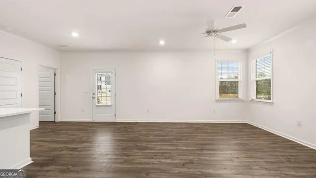 a view of empty room with wooden floor and fan
