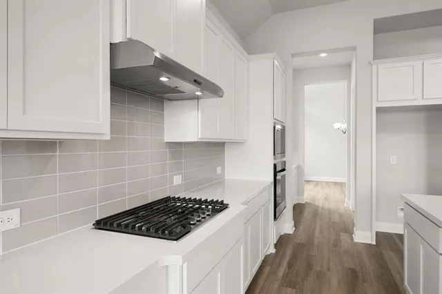 a kitchen with granite countertop a sink a toilet a refrigerator and cabinets