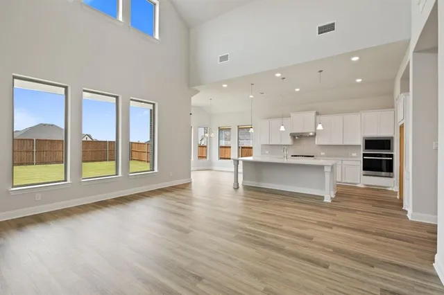 a view of an empty room with kitchen and window