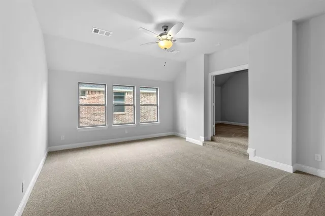 an empty room with chandelier fan and windows
