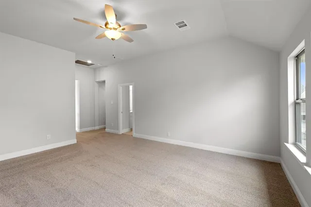 an empty room with windows and ceiling fan