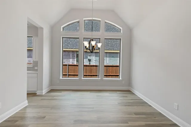 an empty room with wooden floor empty shelves and windows